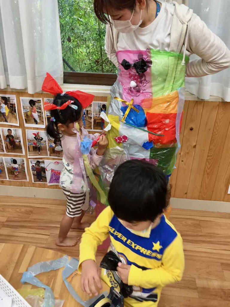 先生が身に着けた服に飾りを付ける子どもたち