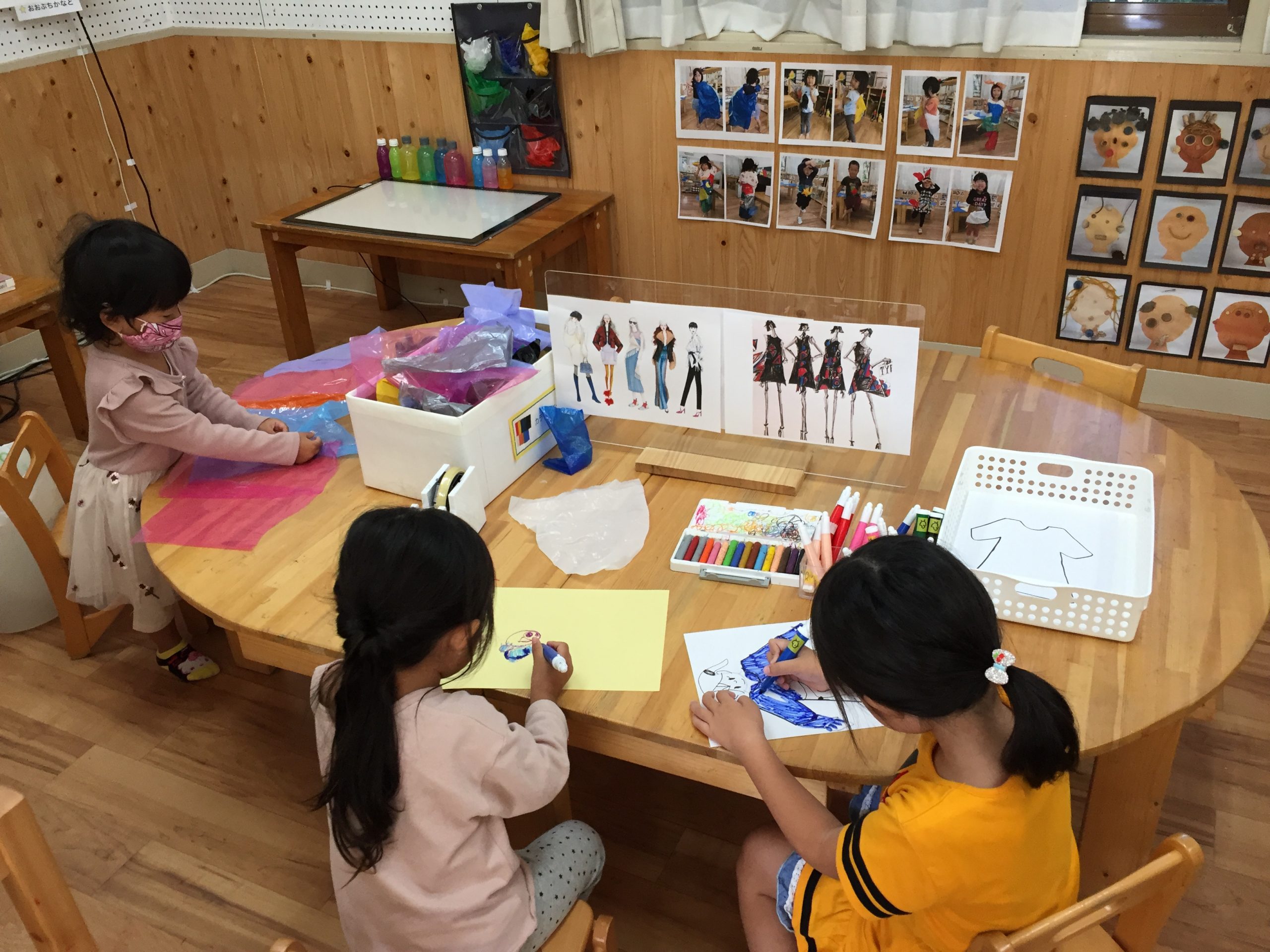 カラービニールやデザイン画を用意した場所で服を作る子どもたち