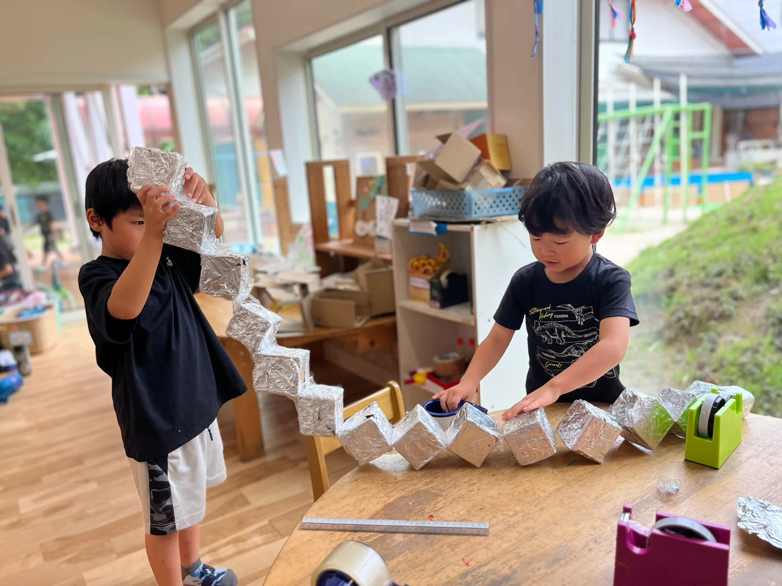 つながった段ボールの製作物と子どもたち