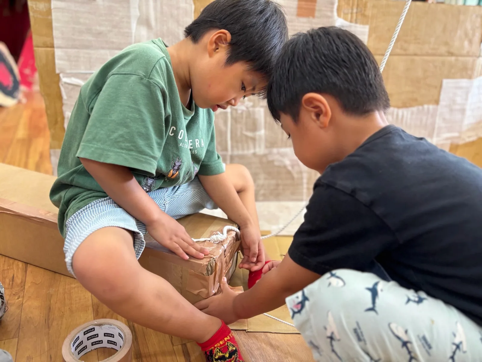 段ボールの製作に一緒に取り組む子どもたち