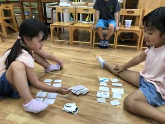 床に座り、自分たちで作ったトランプで遊ぶ子どもたち
