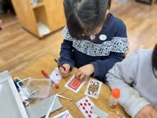 既製のトランプを紙に重ねて型を取る子ども