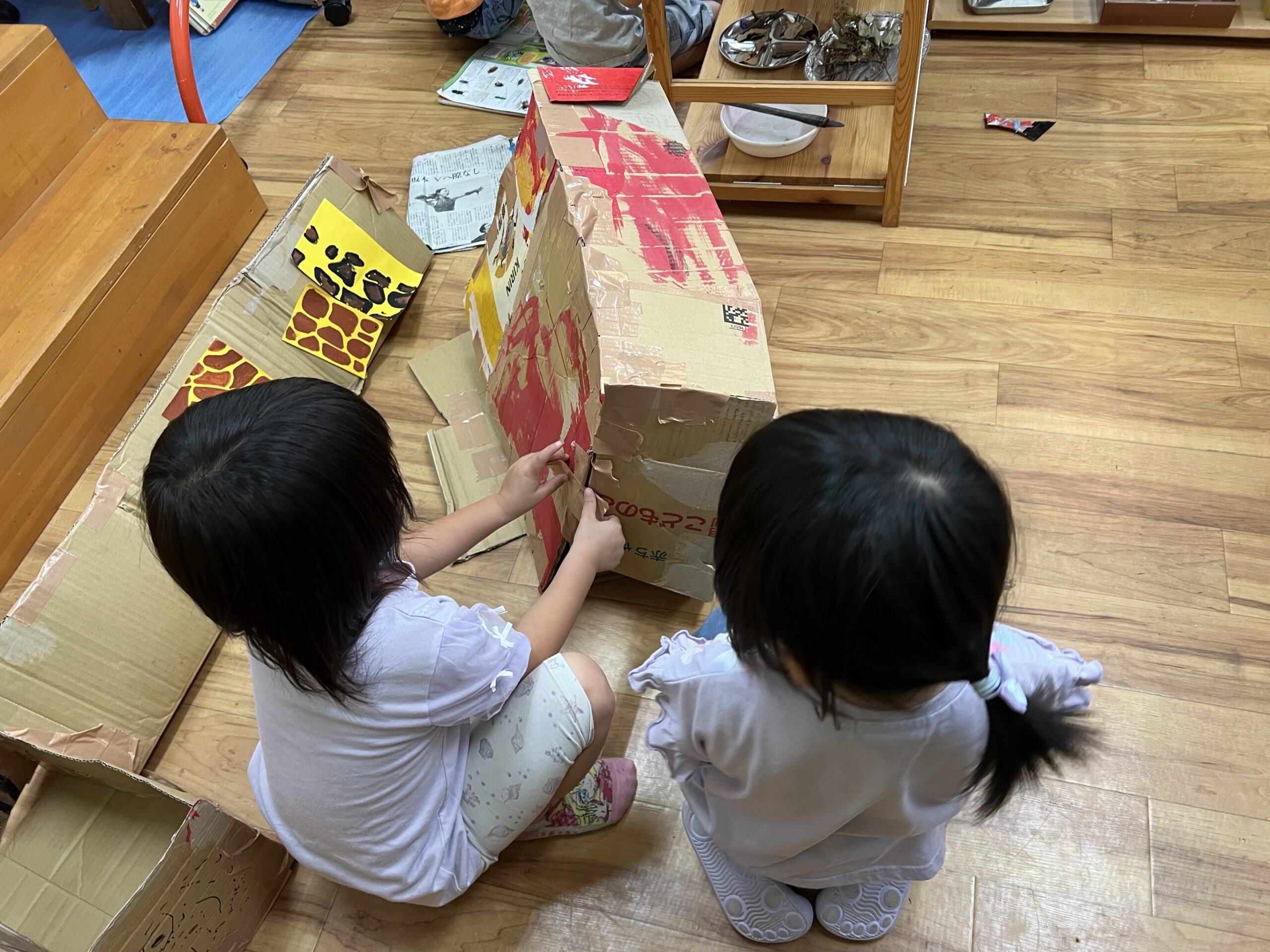 段ボールを組み合わせてキリンの体を作る子どもたち
