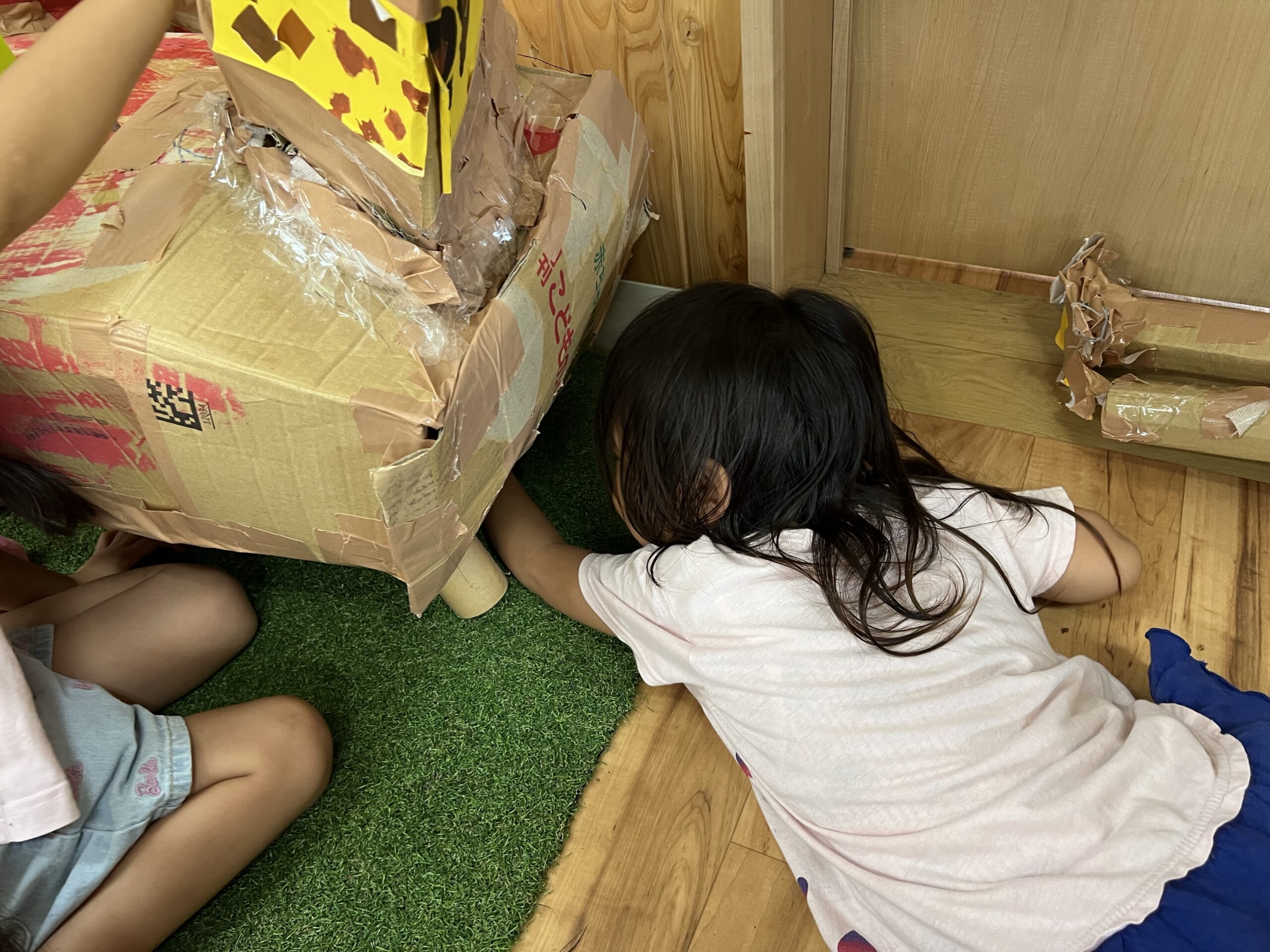キリンの下をのぞき込み、足の様子を確かめる子ども