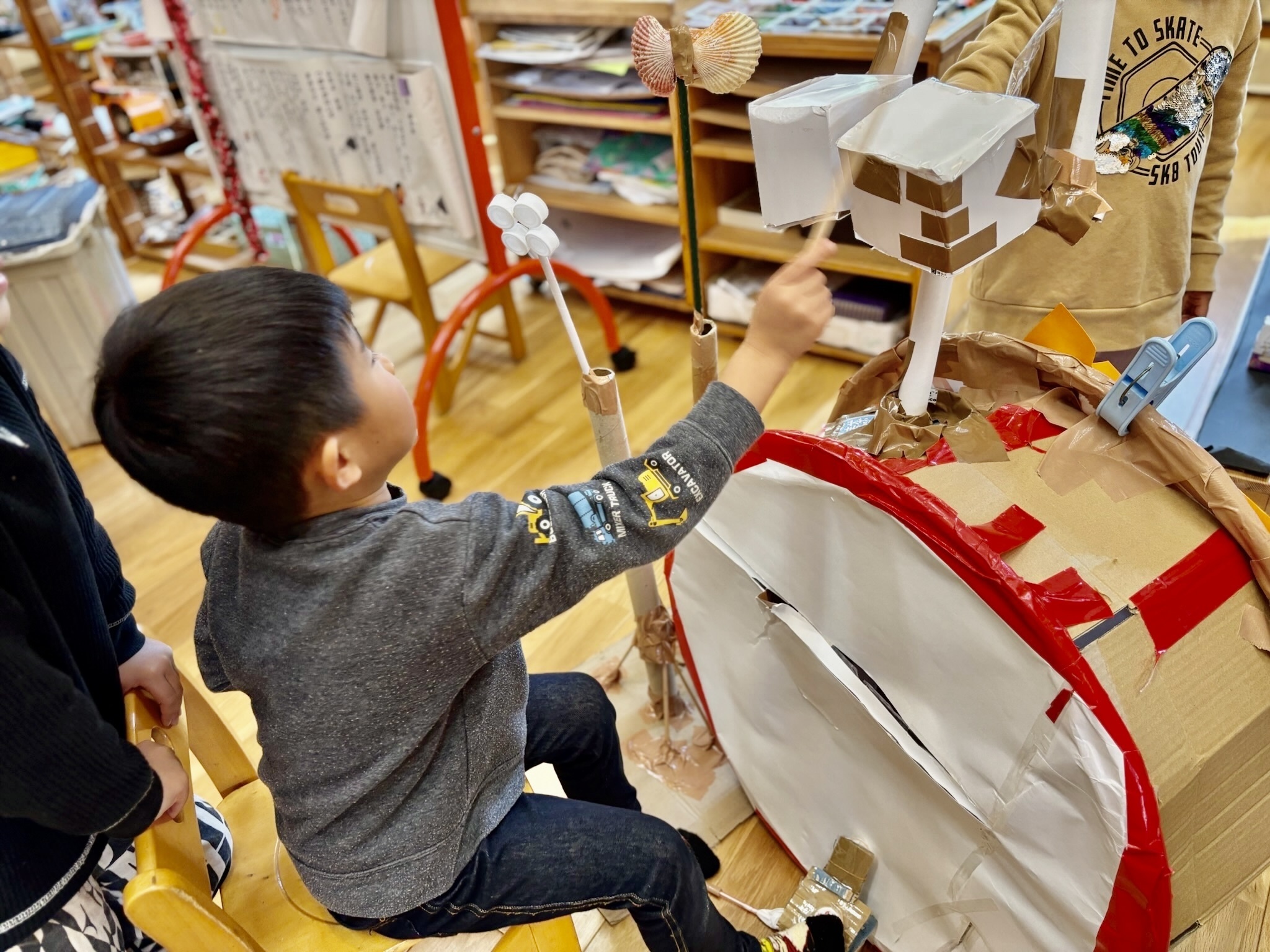 手作りのドラムセットを叩く子どもの姿を後ろから撮った写真