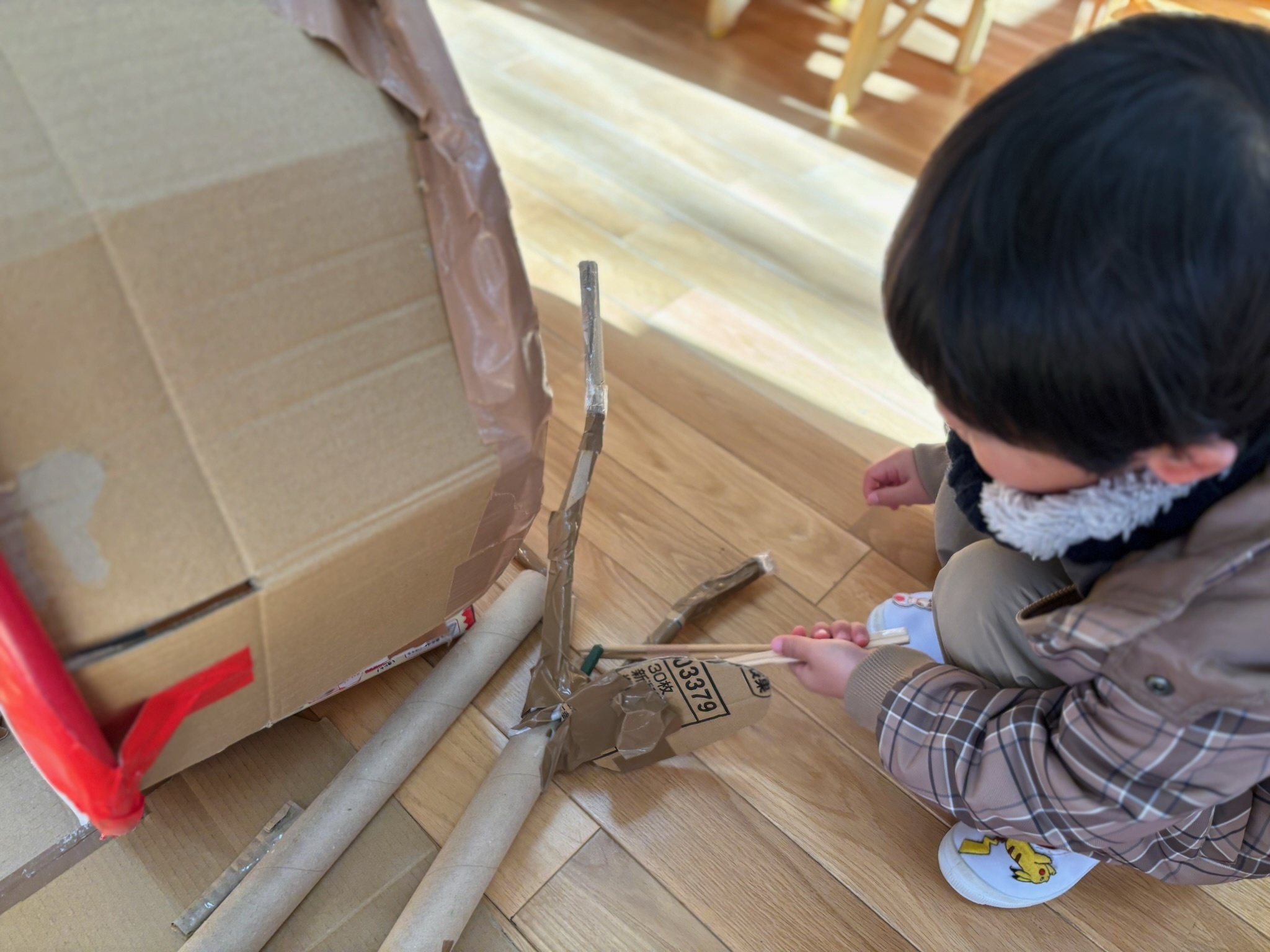 手作りハイハットの棒とペダルのつなぎ方を確かめる子ども