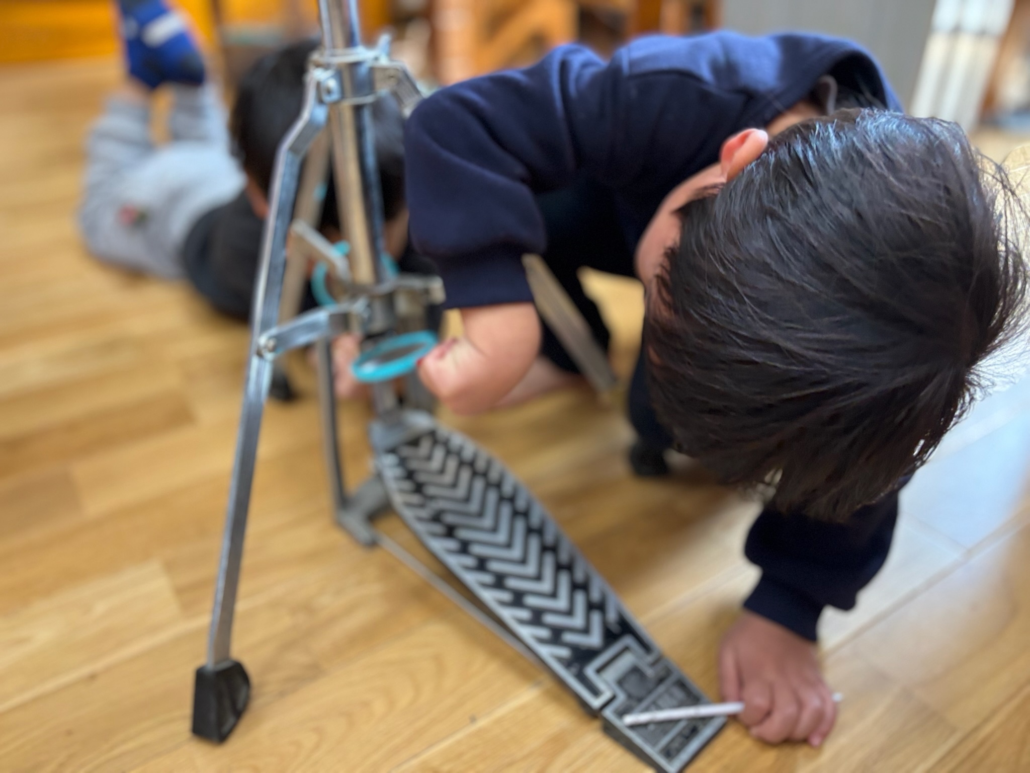 本物のハイハットのペダルと支柱を近くで観察する子どもたち