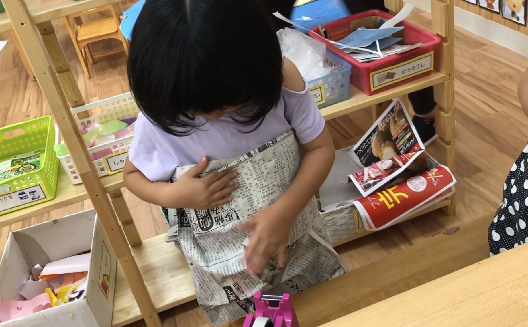 自分で作った新聞紙のドレスを着る子ども